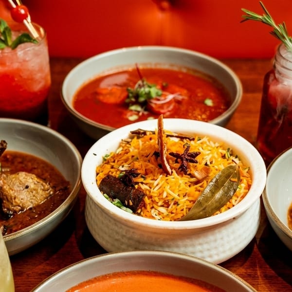 A table filled with various Indian dishes, including biryani, curries, and colorful cocktails.